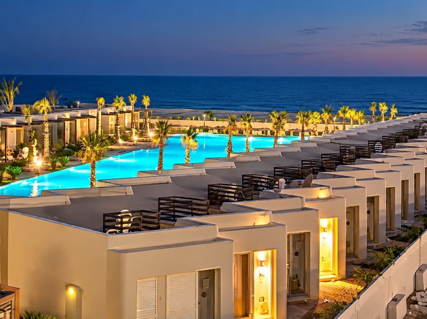 Hacienda West on the North Coast at dusk, with the sea behind a lit pool